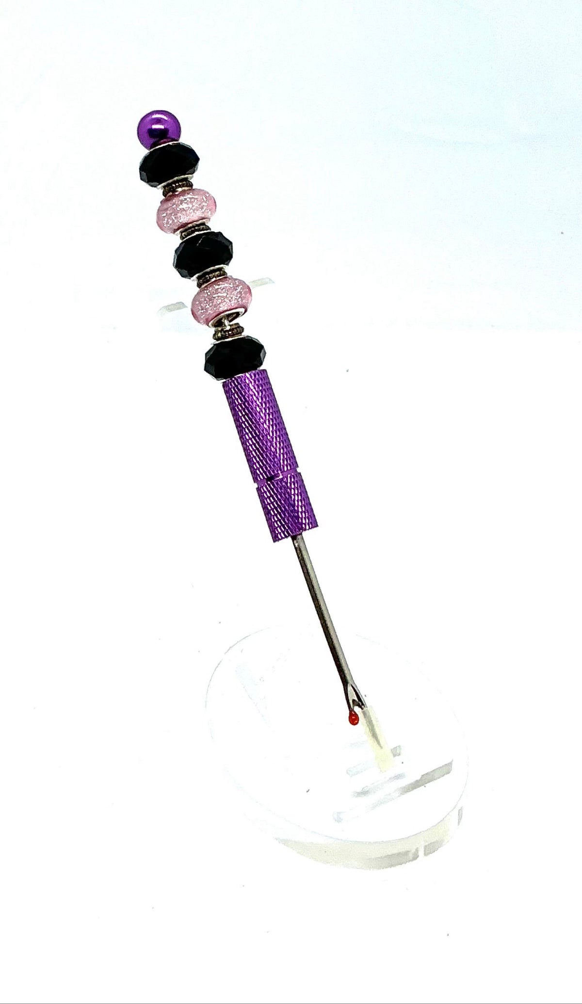 Beaded seam ripper with black faceted and pink glitter beads on a purple handle