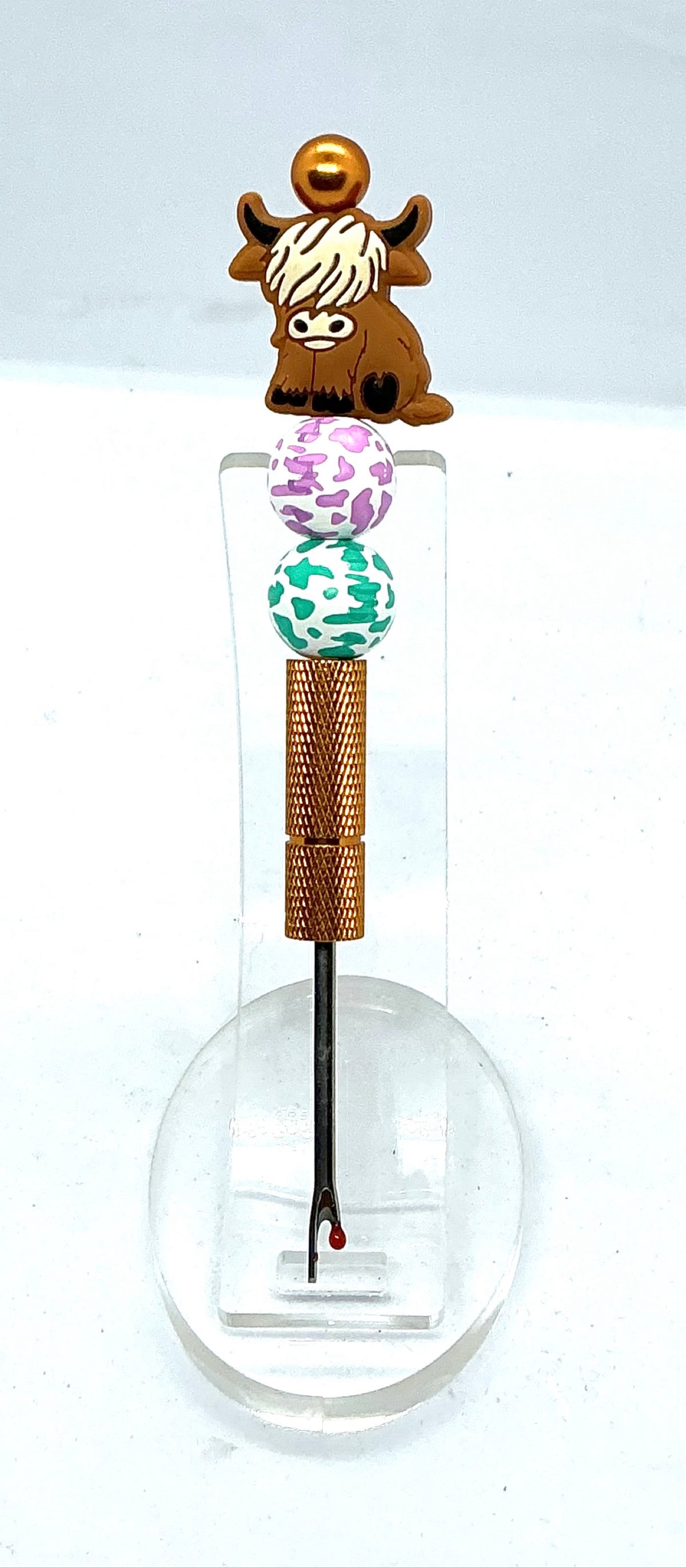 Beaded seam ripper with highland cow focal bead and purple and teal cow print beads on a gold handle