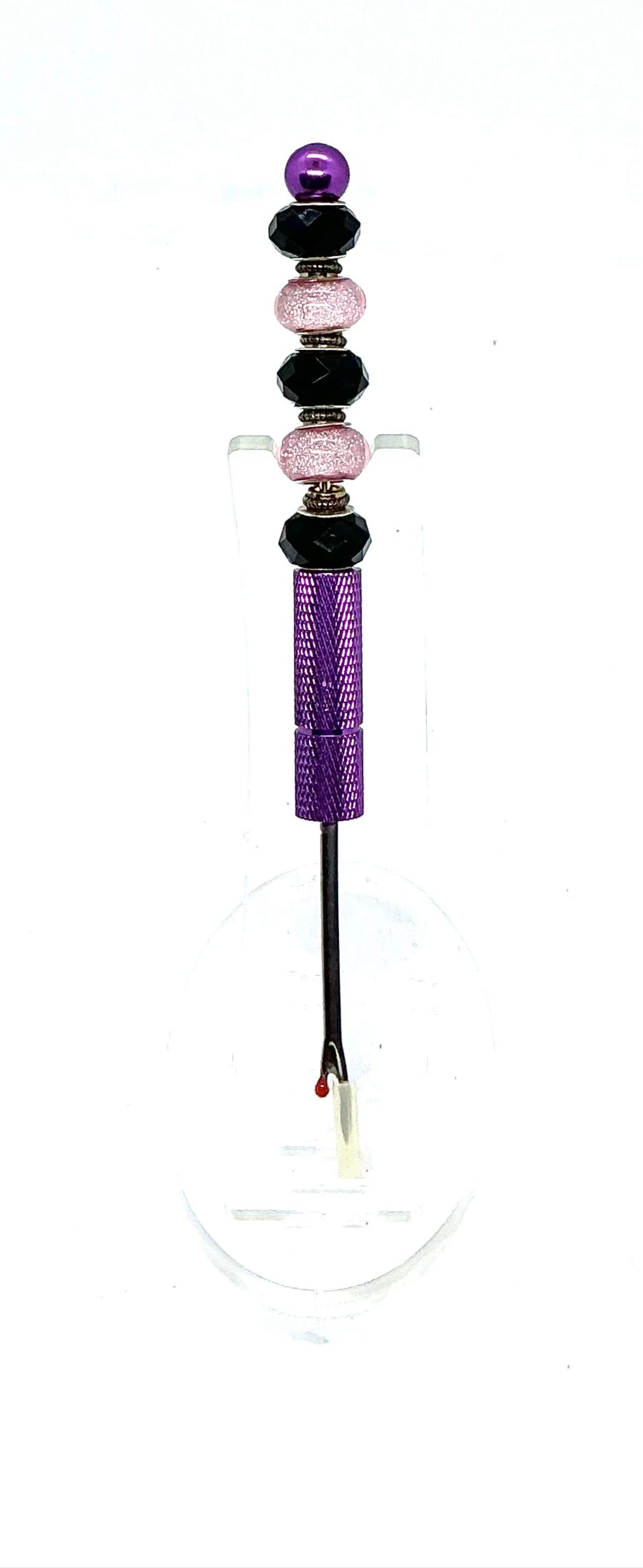 Beaded seam ripper with black faceted and pink glitter beads on a purple handle