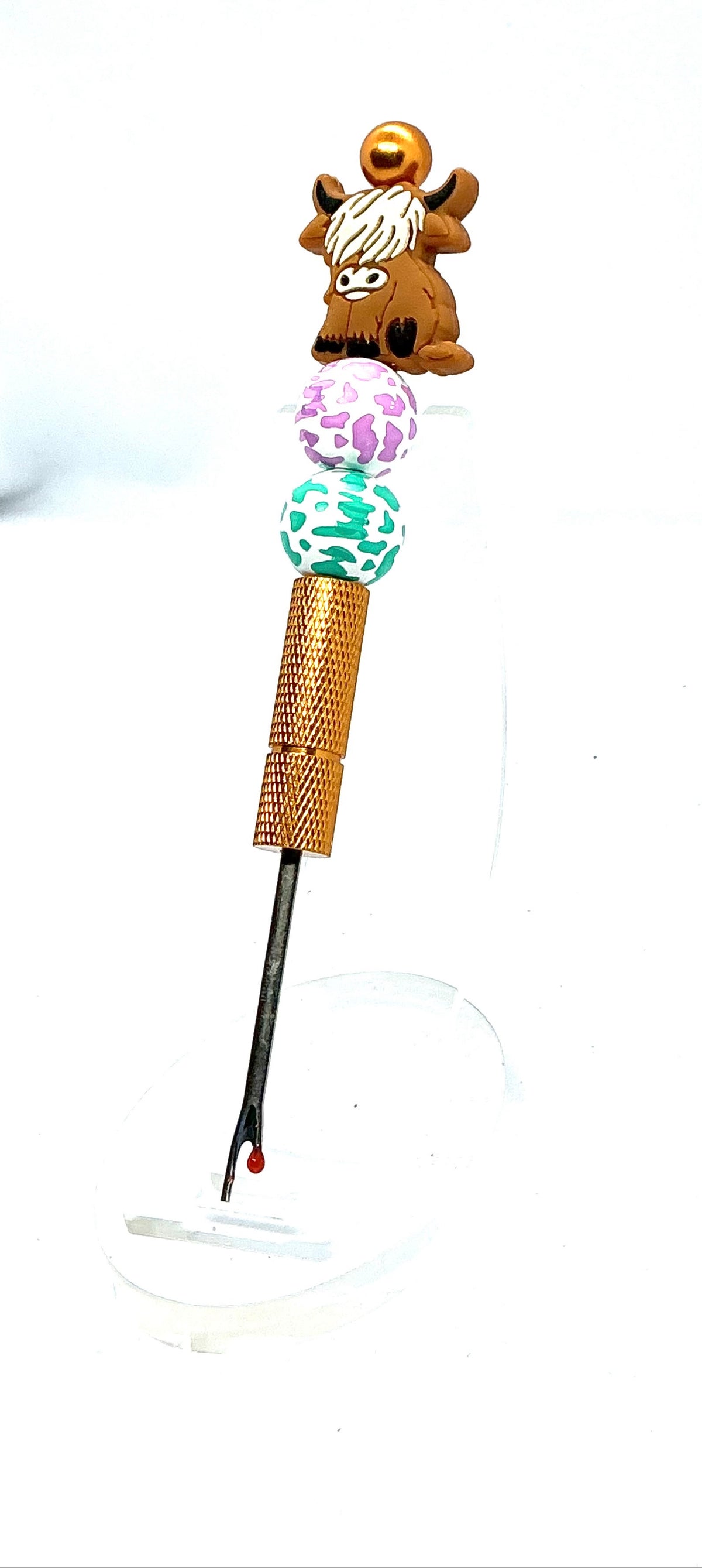 Beaded seam ripper with highland cow focal bead and purple and teal cow print beads on a gold handle