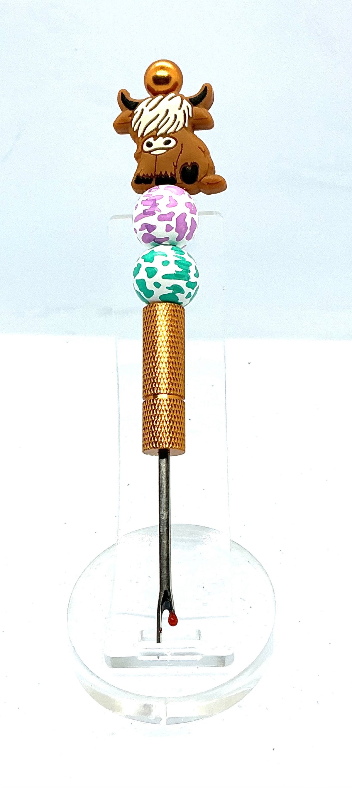 Beaded seam ripper with highland cow focal bead and purple and teal cow print beads on a gold handle