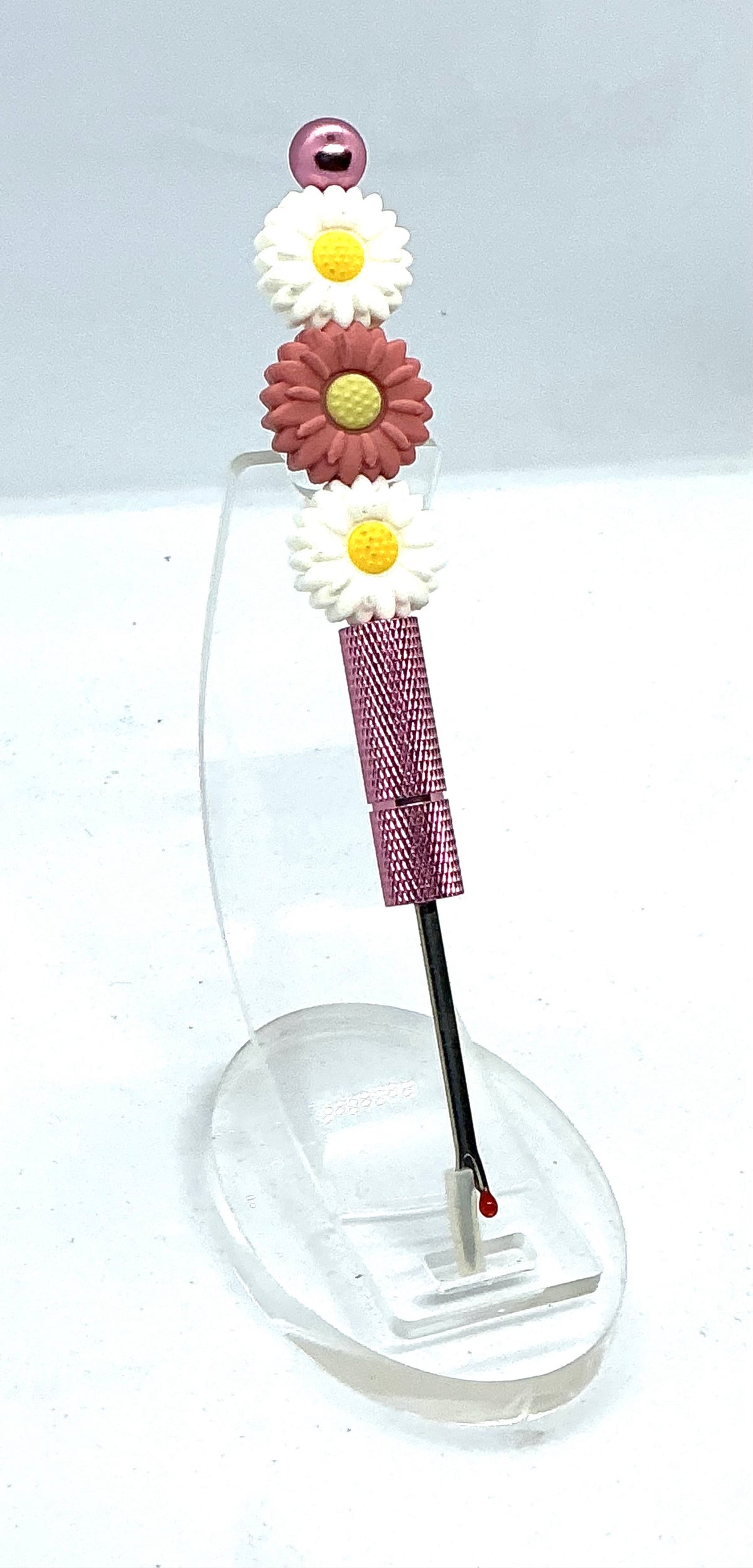 Beaded seam ripper with white and dusty rose daisy beads on a mauve-pink handle