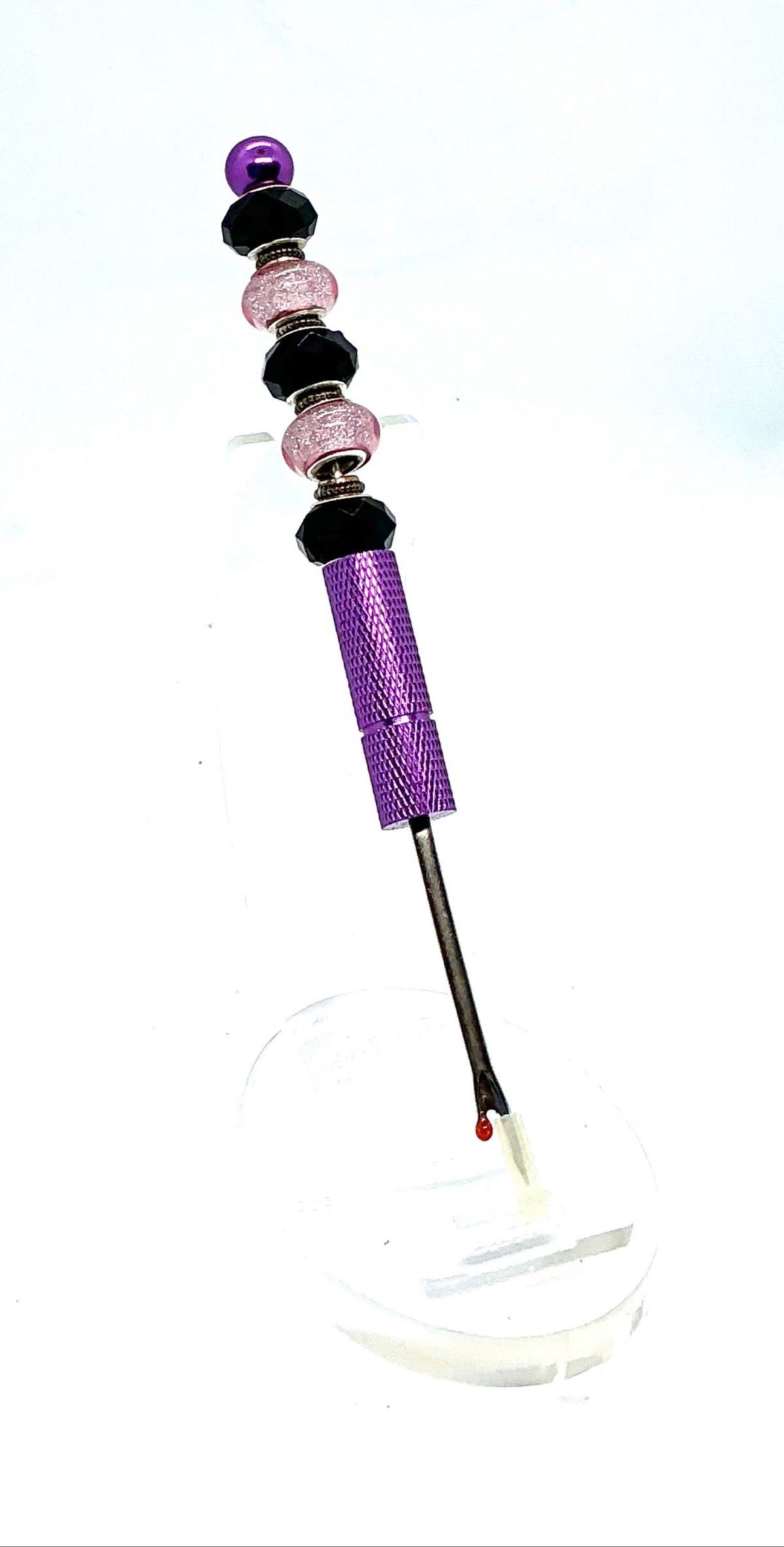 Beaded seam ripper with black faceted and pink glitter beads on a purple handle
