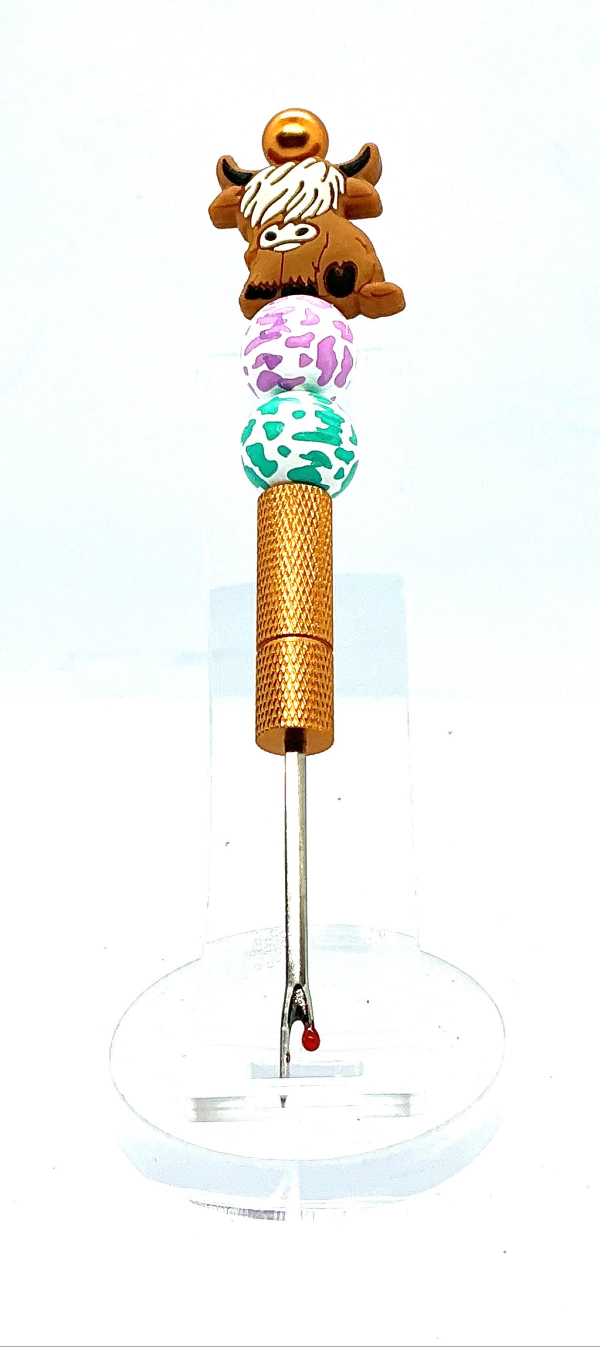 Beaded seam ripper with highland cow focal bead and purple and teal cow print beads on a gold handle
