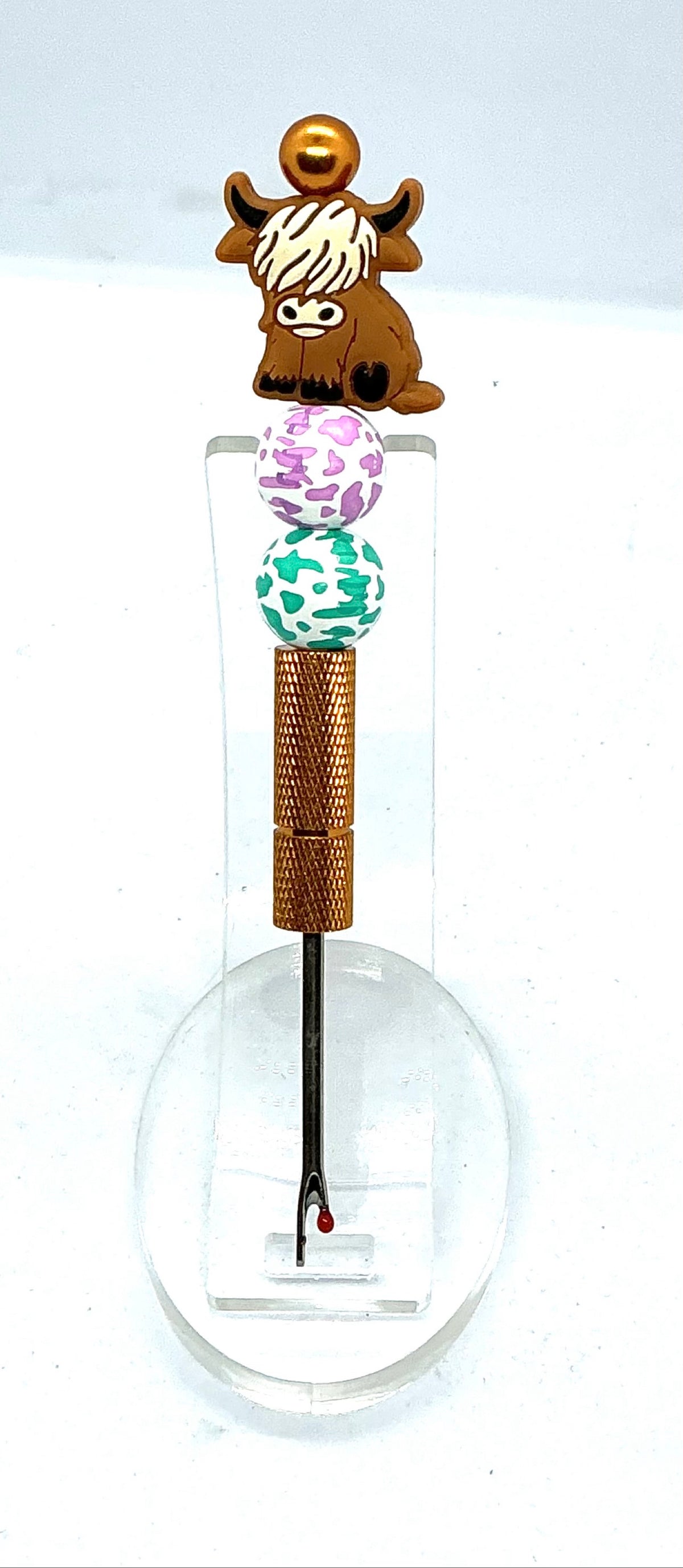 Beaded seam ripper with highland cow focal bead and purple and teal cow print beads on a gold handle