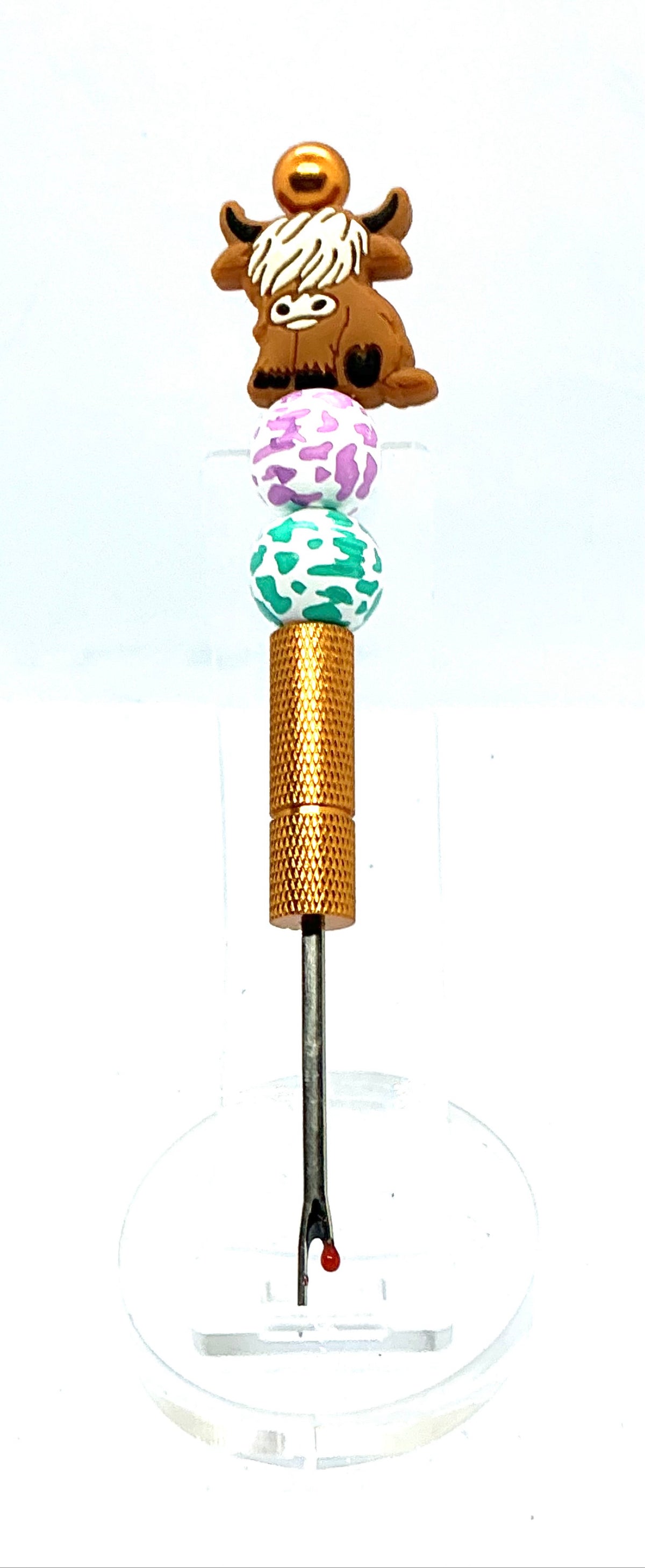 Beaded seam ripper with highland cow focal bead and purple and teal cow print beads on a gold handle